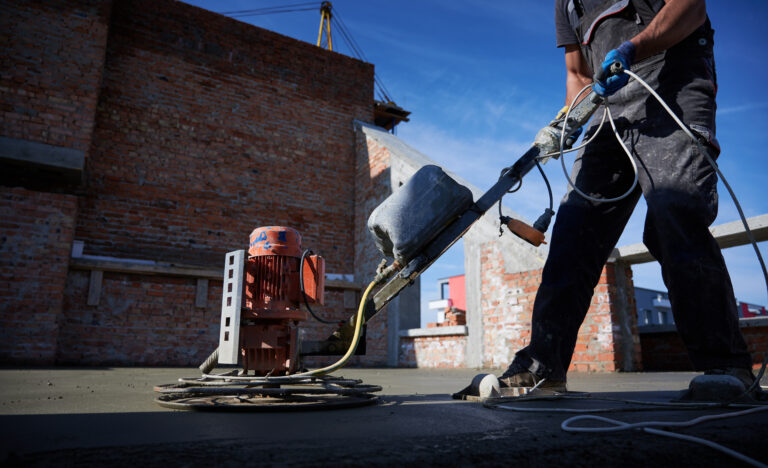 Male worker using concrete screed machine at construction site